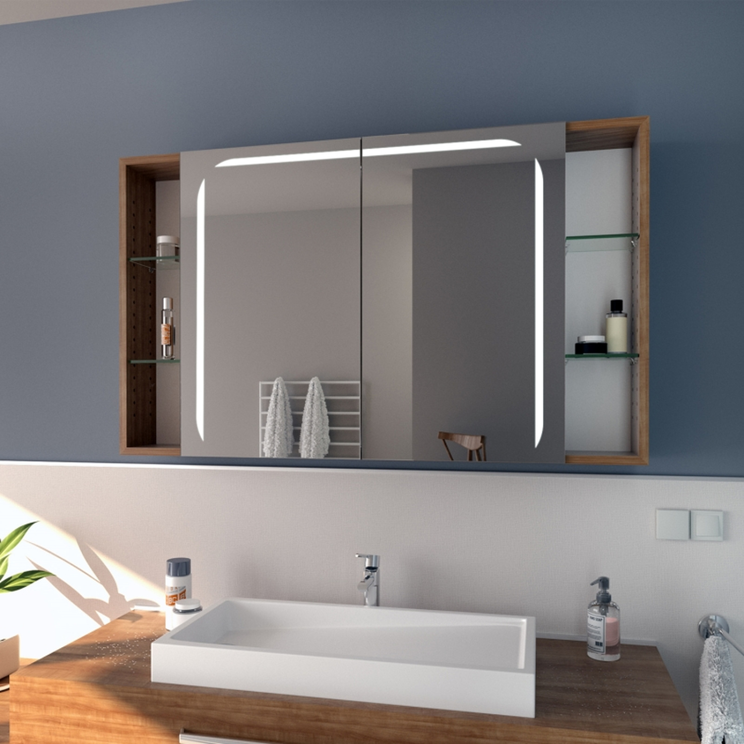Spiegelschrank STORD mit LED-Beleuchtung, Seitenansicht, zwei Spiegeltüren mit seitlichen Holzregalen in Nussbaumoptik, über weißem Waschtisch mit Holzplatte, schwarze Armaturen, graue Wand, Grünpflanze